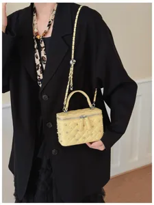 Detailed view of fashionable yellow quilted vanity chain bag with rhinestones and pearls.