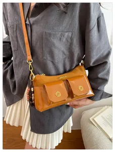 Détail sac marron multi-poches, combinaison élégante de cuir verni et de suède fin.