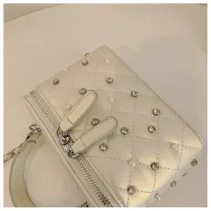 Detail view of a chic white quilted vanity bag featuring pearl and rhinestone embellishments.