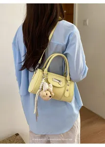 Chic yellow bowling shoulder bag detail shot, stylish leather pillow handbag with charm.