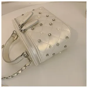 Close-up of a white quilted vanity handbag featuring shimmering rhinestones and chain strap.
