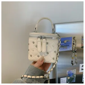 Detailed shot of white quilted vanity bag featuring sparkling rhinestones, pearls and chic chain strap.