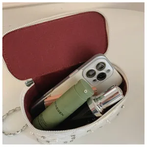 Detailed view of white quilted chain bag interior showing capacity with phone and cosmetics inside.