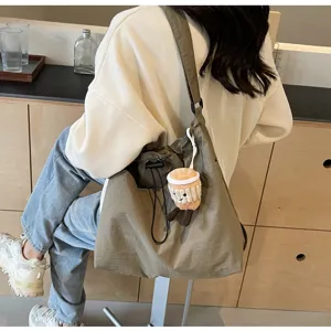 Casual canvas shoulder bucket bag with cute plush coffee cup charm for women commute.