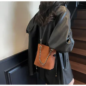 Sac seau élégant en suédine marron avec bandoulière chaîne et cordon pour le quotidien.