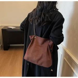Vue détaillée du sac porté épaule en daim marron avec bandoulière chaîne, style rétro.
