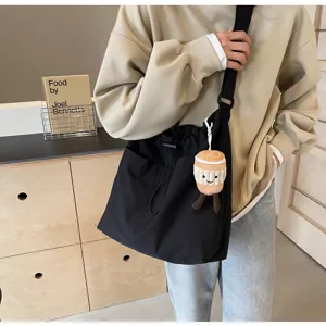 Detail shot of black canvas shoulder bucket bag with casual design and cute pendant accessory.