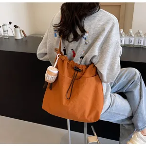 Large capacity casual orange canvas shoulder bag, trendy bucket bag with drawstring for women commute.