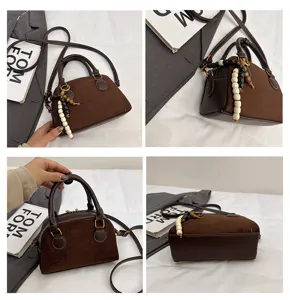 Detailed view of retro brown suede bowling bag with elegant bead pendant and top handle.