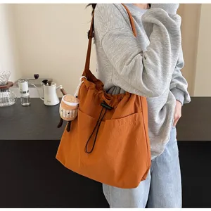 Casual canvas shoulder bag detail view showing large capacity, drawstring closure and cute pendant.