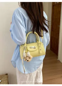 Detail shot of women's trendy rivet bowling pillow bag, chic yellow crossbody shoulder handbag.