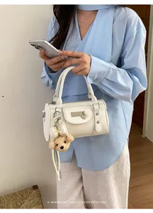 White bowling pillow bag detail showing soft PU leather, metal hardware, and cute bear charm.