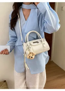 Close-up detail of the stylish white bowling shoulder bag featuring a cute plush bear pendant.