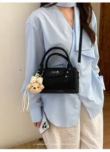 Black bowling shoulder bag for women, retro cylinder handbag with cute plush charm and rivet details.