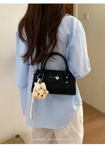 Trendy black bowling shoulder bag with cute bear charm and rivets for women daily commuting.