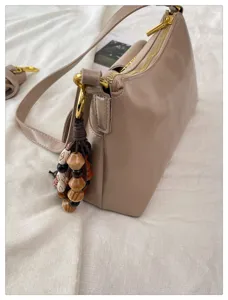 Vue détaillée d'un sac porté épaule beige en cuir PU avec accessoires en métal et perles.