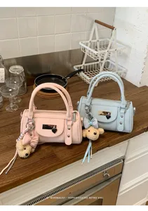 Detail shot of trendy pastel pillow bowling bag with cute bear charm and metal rivet accents.
