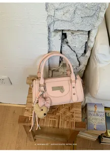 Pink bowling bag detail featuring chic metal rivets, heart lock, and cute plush bear charm.