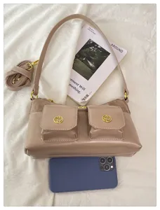 Gros plan sur le sac axillaire chic à multi-poches avec poches avant doubles et quinzallerie dorée.