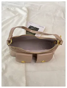 Vue détaillée du sac porté épaule beige avec deux poches à rabat et détails dorés.