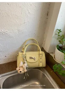 Detailed close-up of yellow stylish bowling bag featuring a cute bow bear charm and sleek design.