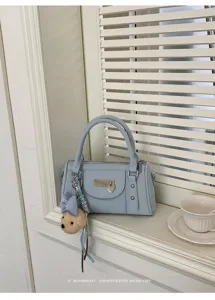 Detailed view of the light blue bowling bag on a windowsill, featuring a cute bear charm and retro style.