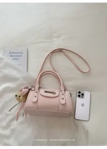 Pink leather bowling shoulder bag, minimalist retro design with metal rivets and cute bear charm.