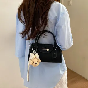 Trendy black bowling shoulder bag for women, casual rivet handbag with cute dog pendant and bow.