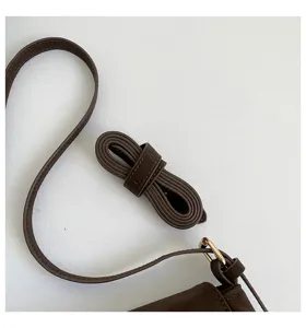 Detail shot of a stylish brown PU leather handbag strap and hardware buckle component.