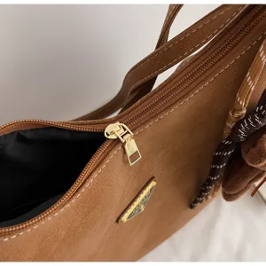 Brown PU leather shoulder bag detail showing golden metal zipper and classic triangle logo plaque.