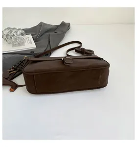Detail view of the dark brown vintage shoulder bag, featuring metallic buckle and strap.