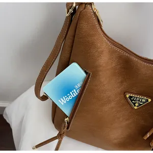 Brown PU leather shoulder bag with zipper pocket and stylish triangular metal logo plaque.