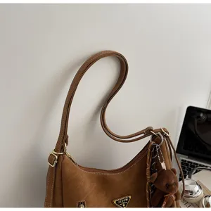 Brown PU leather shoulder bag detail closeup with metal hardware and cute bear pendant charm.