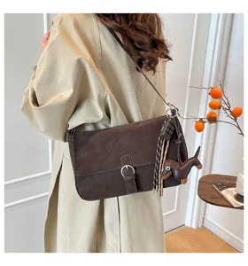 Retro brown shoulder bag detail showcasing vintage buckle design, charm and premium winter style.