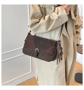 Close-up detail of retro dark brown underarm shoulder bag with metal buckle and charm decor.