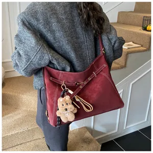 Detailed view of the vintage maroon suede shoulder tote bag with cute plush bear pendant.
