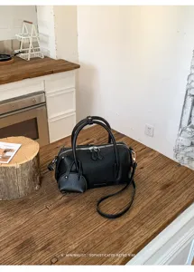 Close-up detail of black leather Boston shoulder bag with textured surface and chic design.