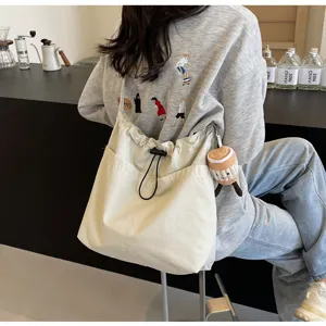 Detail view of casual canvas bucket bag in off-white with drawstring and front pocket.