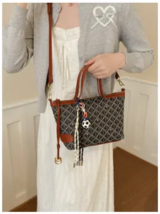 Vue de détail d'un sac seau rétro pour femme avec pendentif chic et bandoulière élégante.