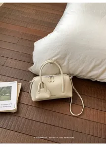Detail view of stylish beige litchi grain boston pillow shoulder crossbody bag in cozy setup.