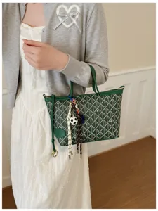 Detail du sac a main vert imprime, motif chic avec charmants pendentifs et anses elegantes.