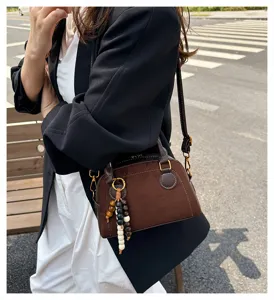 Retro brown suede bowling bag detail, elegant wooden bead pendant and delicate golden hardware.