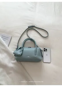 Light blue litchi pattern leather Boston pillow handbag with shoulder strap and mini pouch.
