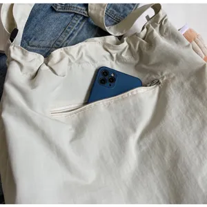 Casual canvas shoulder bag detail view showing front zipper pocket and soft fabric texture.