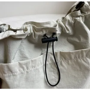 Casual nylon drawstring bucket bag with adjustable black cord and front pocket detail.