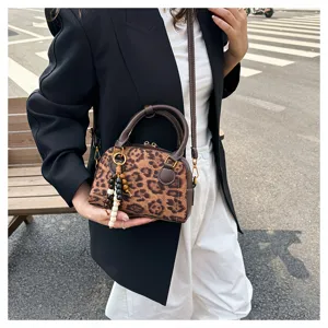 Detail shot of the vintage leopard print bowling bag with brown handle and beaded charm accessory.