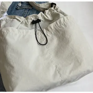 Close-up detail of the casual beige drawstring bucket shoulder bag with adjustable cord lock.