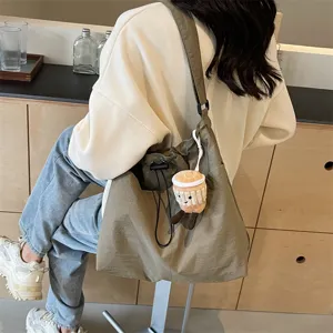 Large capacity casual canvas shoulder bag for women, stylish commuter bucket bag with cute pendant.