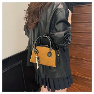 Detail view of vintage retro brown suede bowling bag handbag with shoulder strap and pendant.