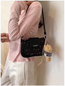 Détail du sac porté épaule noir à motif d'étoiles avec charm ours et design à rabat.